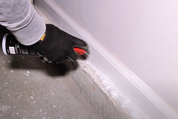 a foam insecticide being applied along a baseboard