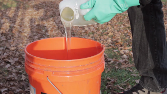 Image of a person mixing pest control liquid in a bucket