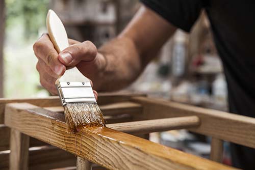 Image of a man sealing wood with a paintbrush